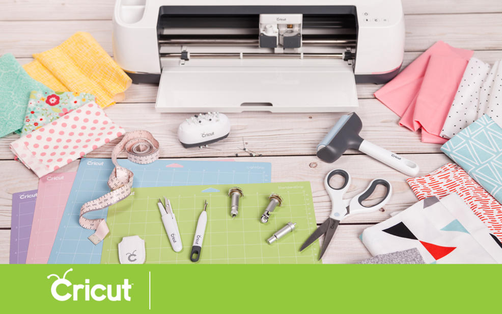 Cricut Logo. A variety of sewing equipment rests on a table.